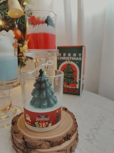 Macro view of Christmas tree shaped scented soy candle in glass with wood coaster