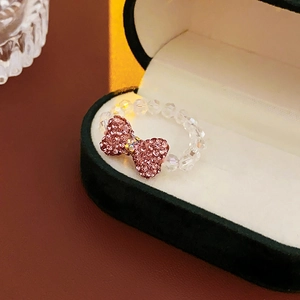 Close-up of pink bow ring with micro-set rhinestones and transparent crystal beads