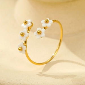 Detail of 18K gold titanium steel flower ring with white enamel and zircon accents