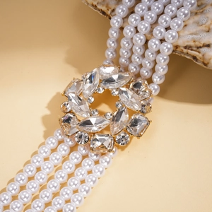 Close-up of multilayer pearl necklace with diamond floral clasp on a seashell