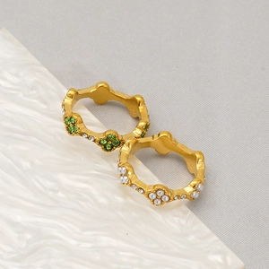 Detailed close-up of 18K gold clover rings with micro-pave crystals and emerald stones