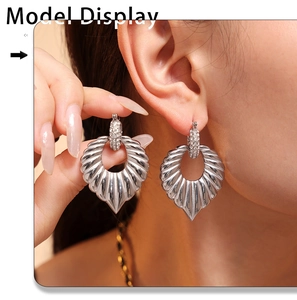 Macro view of silver fan-shaped textured earrings with sparkling diamond studs on model