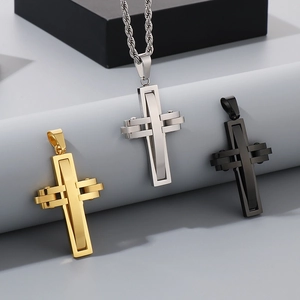 Close-up of hip-hop cross pendants in silver, gold, and black finishes on a textured stand