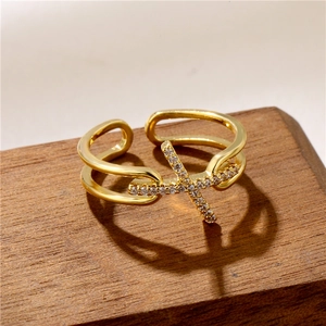Adjustable gold-plated cross ring with pavé zircons on a rustic wooden stand