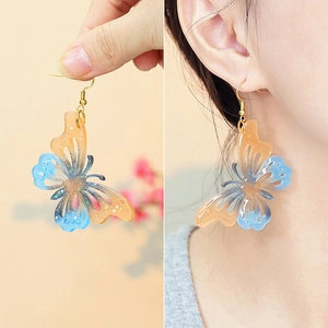 Boucles d'oreilles papillon ajourées avec dégradé bleu-orange et paillettes