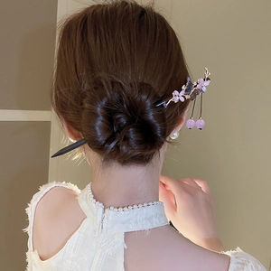 Detail of wooden hair stick with purple floral and butterfly tassels on a hair bun