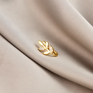Macro shot of gold leaf non-pierced ear cuff with sparkling zircon on soft fabric