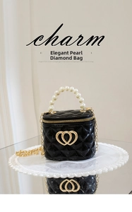 Detail of black quilted mini bag featuring white pearl handle and gold heart clasp