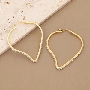 Golden geometric heart earrings with sparkling micro-pave zircons on a marble background