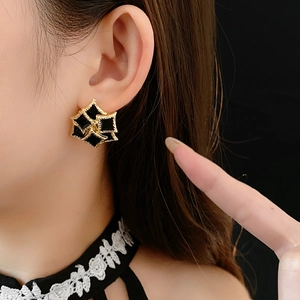 Detail of vintage French style gold square earrings with black enamel on a model