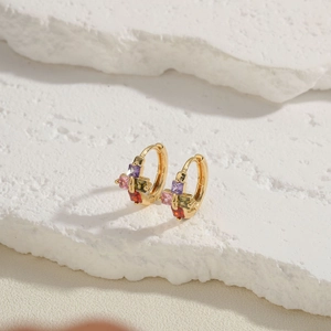 Macro shot of gold huggie earrings featuring multi-color square-cut zircons and textures