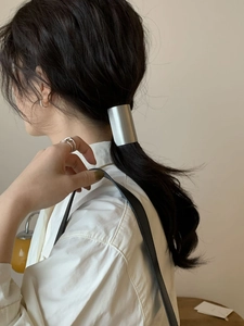 Polished silver metal hair cuff detail on ponytail showing sleek minimalist aesthetic