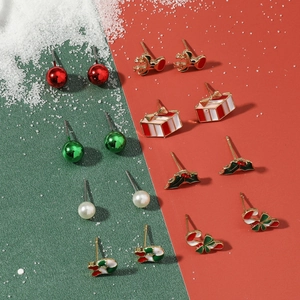 Detailed view of nine pairs of Christmas stud earrings with festive icons on a snowy background