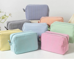 Multiple colorful seersucker makeup bags with striped texture and zip closure in detail