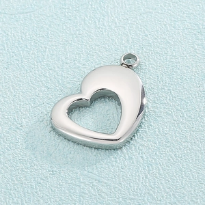 Vue macro d'un pendentif coeur argenté avec finition polie sur une surface bleu clair