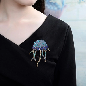 Detail of a jellyfish brooch with blue crystals and golden tassels on a black sweater