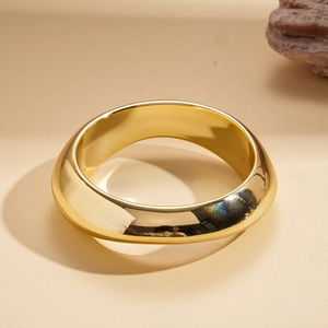 Close-up of a wide polished gold irregular geometric bangle with a mirror finish