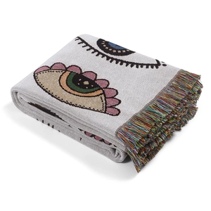 Close-up of bohemian knit throw blanket featuring eye pattern and colorful fringe