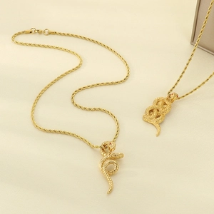 Detail of 18k gold snake pendant with red gemstone eyes and elegant twisted rope chain