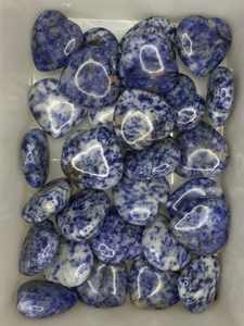Macro shot of multiple heart-shaped blue and white sodalite stones in a white tray