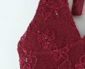 Macro detail of burgundy mesh fabric with flocked 3D floral patterns and sequins