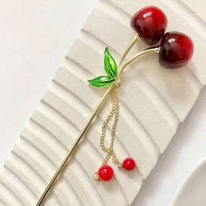 Elegant cherry tassel hair stick with red beads and golden metal chain on a stone base