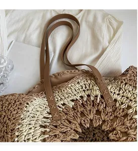 Close-up of woven straw bag with circular floral pattern and brown PU leather handles