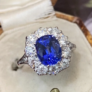 Lujoso anillo de zafiro azul real óvalo con halo de diamantes en joyero de terciopelo