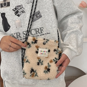 Close-up of plush floral crossbody bag with woven strap and branded label