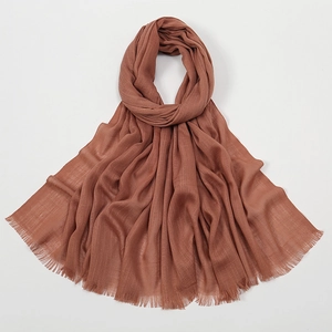 Detailed close-up of brown slub cotton scarf texture with soft fringe edges