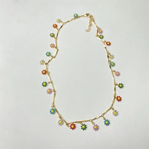 Detail view of colorful enamel daisy charms on a gold chain necklace with adjustable clasp