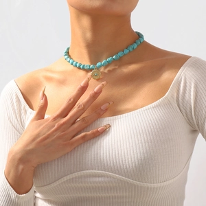 Detail of bohemian turquoise beaded necklace with golden sun evil eye pendant on model