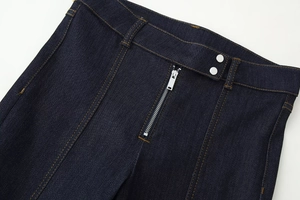 Macro d'un jean bleu foncé montrant la taille avec fermeture éclair et boutons argentés