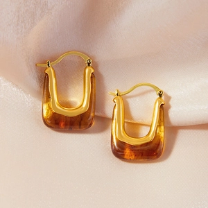 Maillard style vintage gold U-shaped earrings with amber resin on pink silk background