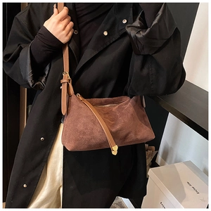 Brown suede crescent bag with adjustable strap styled on a model with black coat