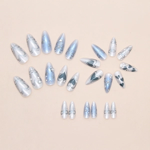Detail view of light blue press-on nails with 3D pearls, rhinestones and star patterns