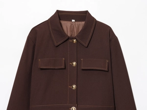 Detail of a brown jacket with contrast stitching, golden metal buttons and chest pockets