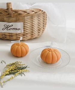 Detail shot of orange pumpkin scented candles with a wick in a cozy home setting