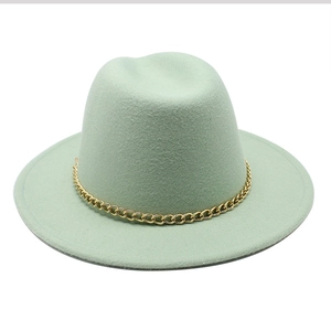 Detailed macro view of mint green wool felt fedora hat featuring a gold chain band