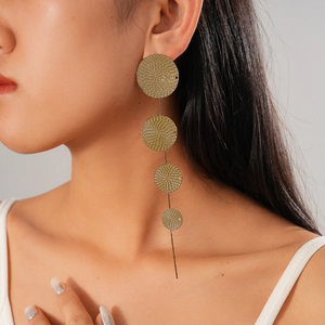 Detail view of gold geometric tiered disc tassel earrings on a model showing dangle length
