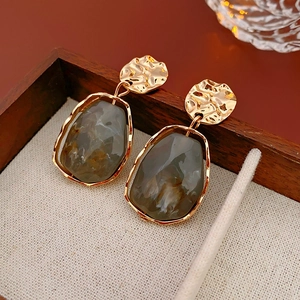 Detail of vintage round hammered metal earring with smoke grey translucent resin drop