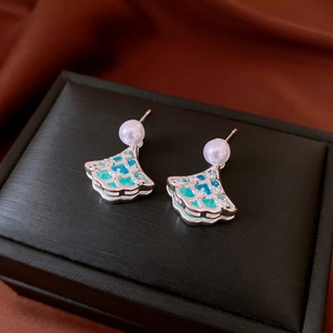 Detail view of silver ginkgo leaf earrings with teal enamel and white pearls on velvet