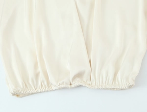 Detailed view of champagne satin fabric with elegant pleated texture and silky finish