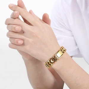 Bracelet en acier titane doré poli avec breloque cœur porté au poignet du modèle