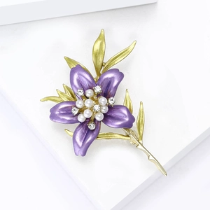 Detailed view of luxury lily brooch with purple enamel and pearl inlay on a display stand
