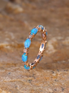 Macro shot of rose gold ring featuring oval blue opals and small pavé zircon details