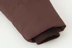 Detail of coffee brown puffer jacket showing windproof sleeve and knitted ribbed cuffs
