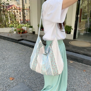 Detail of blue, pink, and white floral print canvas tote bag carried by a model outdoors