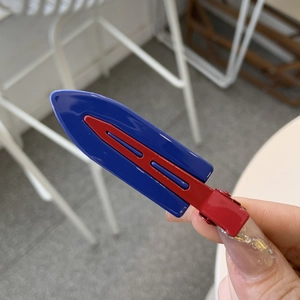 Detail of red and blue contrast hair clip with glossy finish and duckbill metal grip