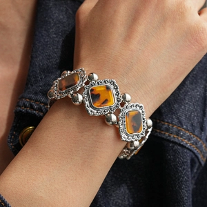 Detail of vintage silver bracelet with amber square resin stones on denim sleeve